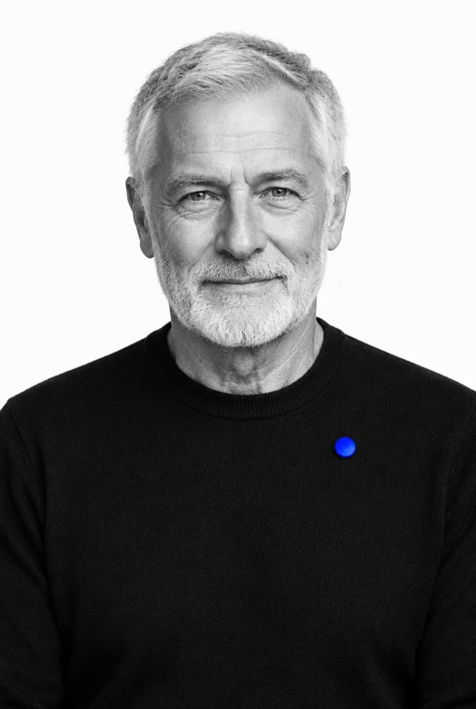 A man in his seventies in black and white wearing one small blue pin